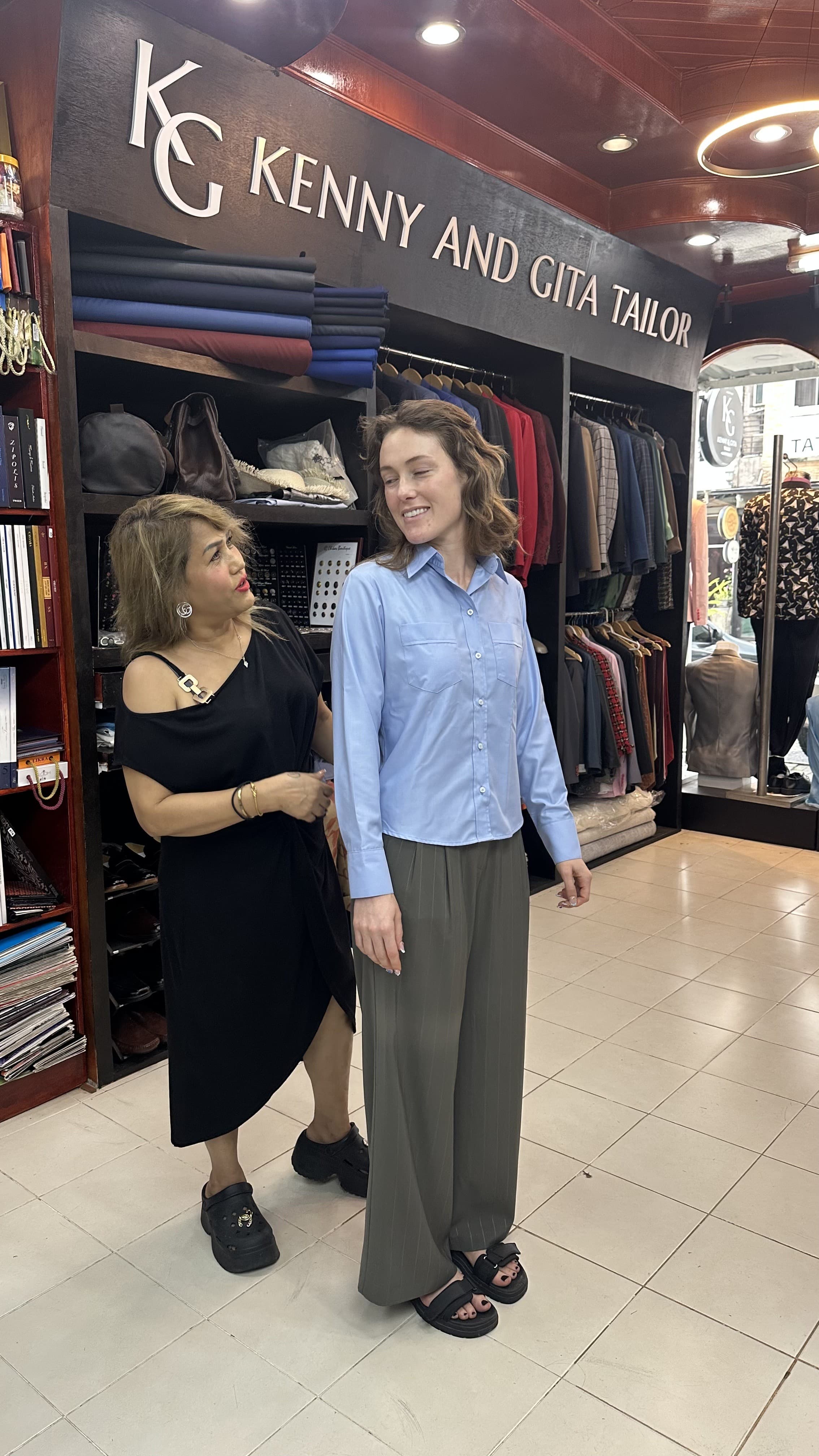Client wearing olive pleated wide-leg trousers with a blue shirt beside Gita