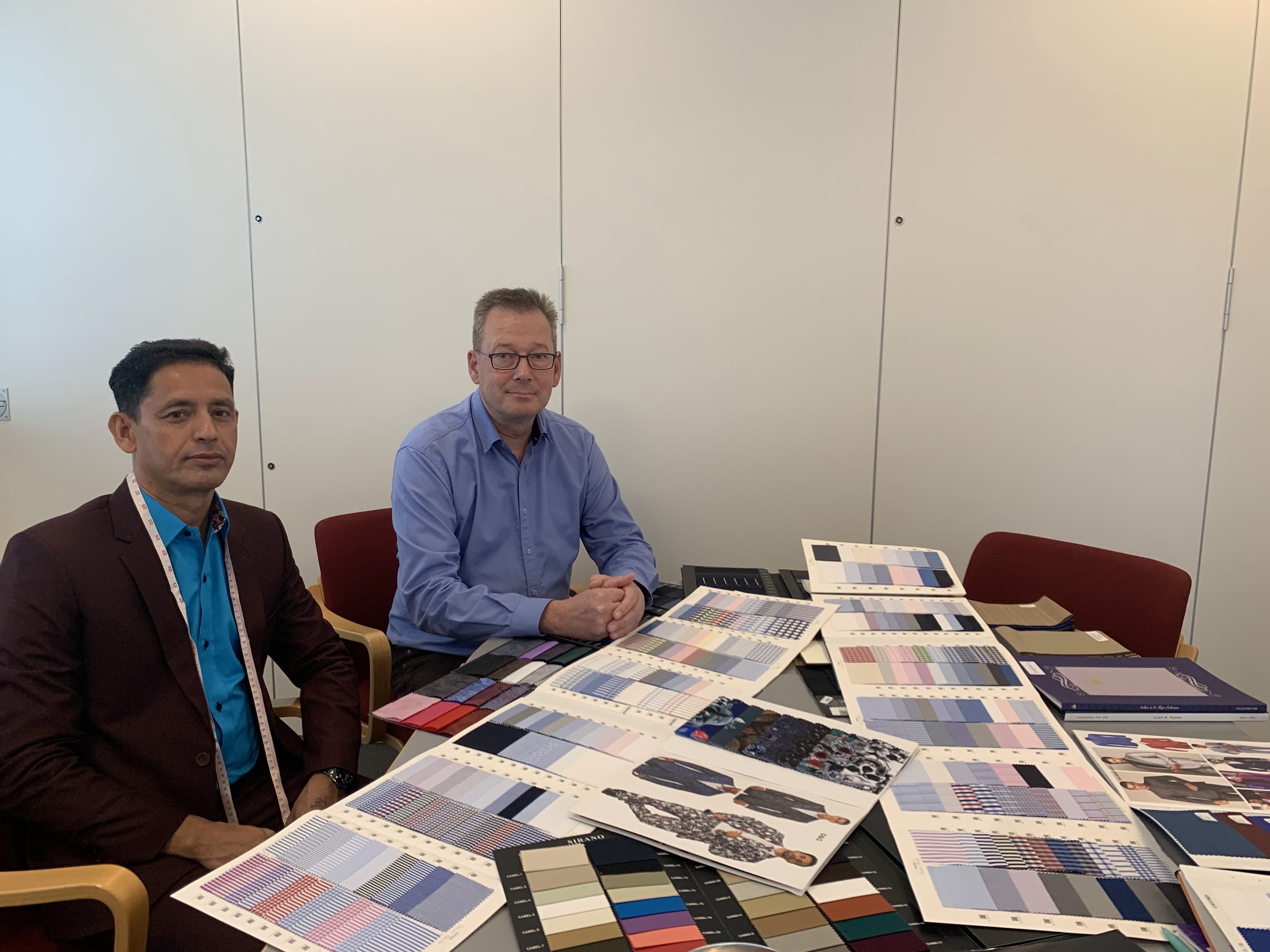 Kenny and a corporate client reviewing shirt and suiting swatches during an overseas consultation