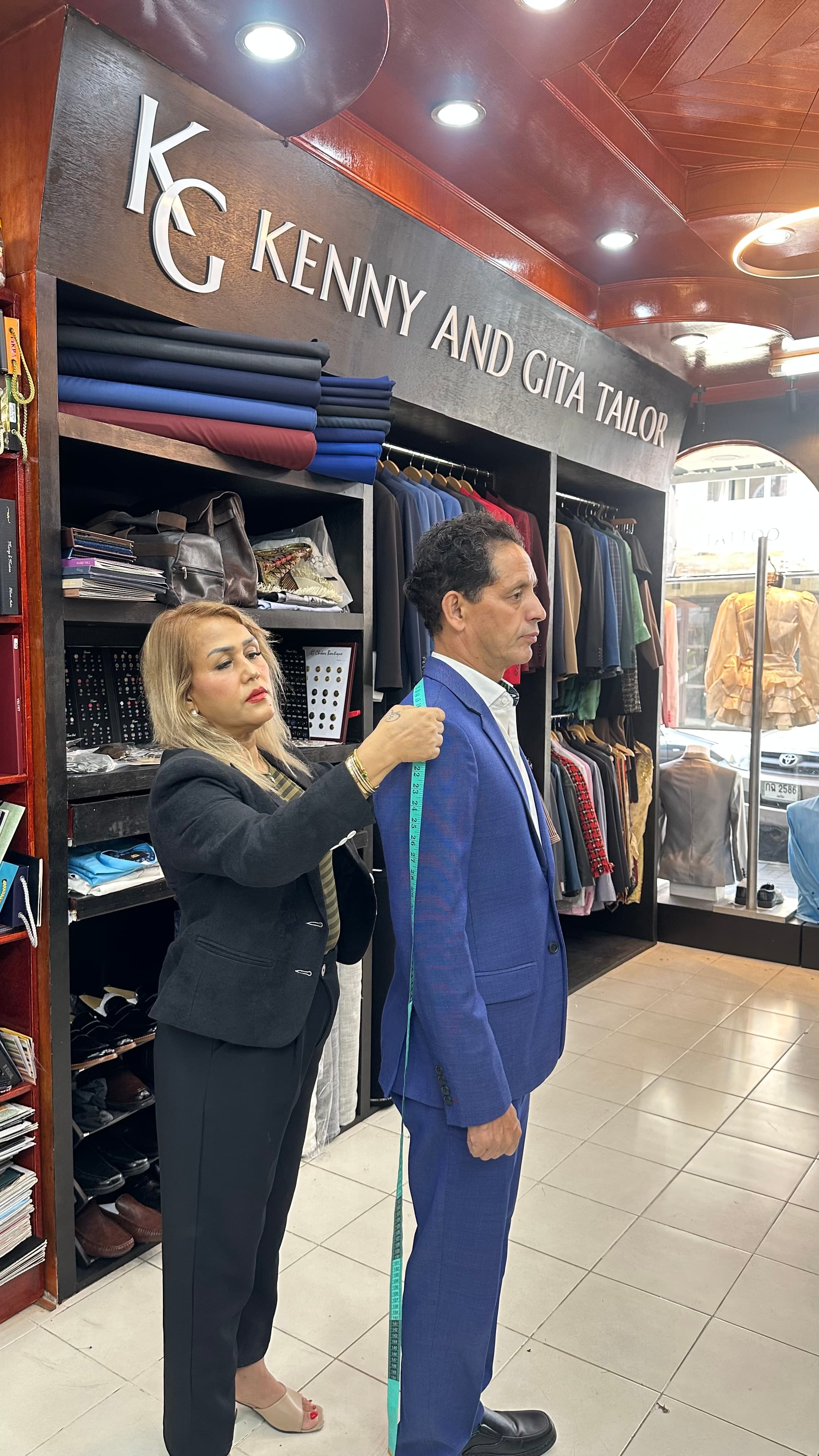 Gita checking shoulder and jacket length during a fitting with Kenny