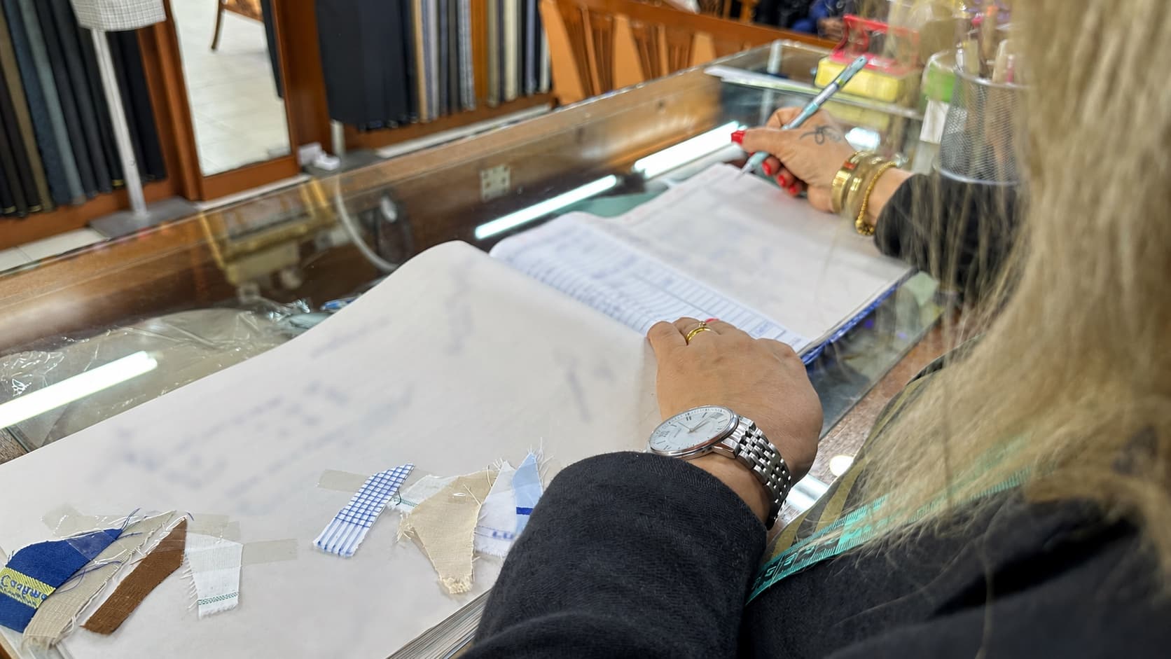 Gita recording garment details beside fabric swatches with all client information obscured