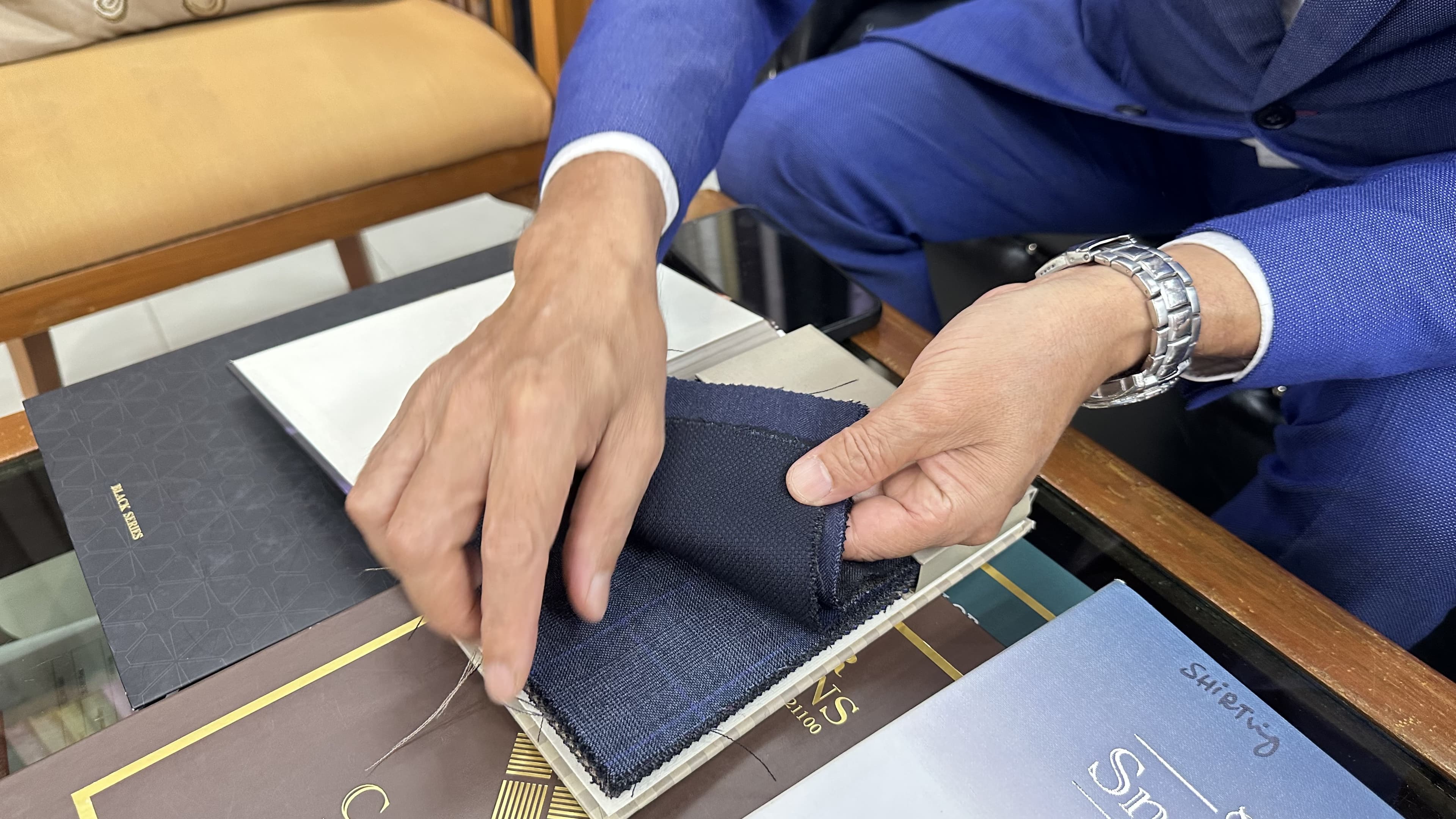 Kenny comparing navy suiting fabrics from an open swatch book