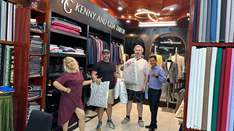 Clients posing with finished bespoke garments inside Kenny & Gita Tailor in Kata, Phuket
