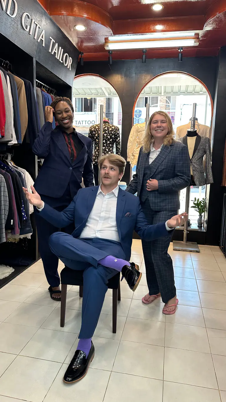 Three clients presenting custom tailoring inside the Kenny & Gita Tailor showroom