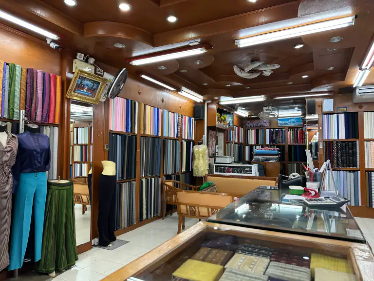 Interior of Kenny & Gita Tailor in Kata, Phuket, with bespoke suits, premium fabrics, and the showroom floor